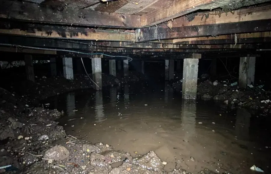 Standing water pooled under the floor framing of a crawl space