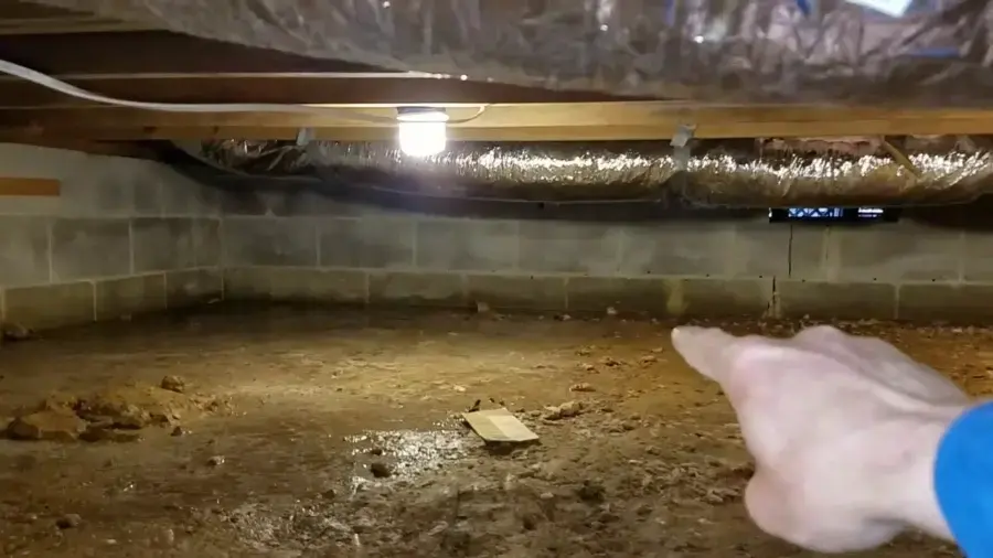 Inspection of wet soil in a block-wall crawl space during a water damage walkthrough